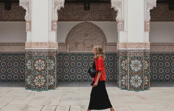 A girl in bright clothes walks near a mosaic wall