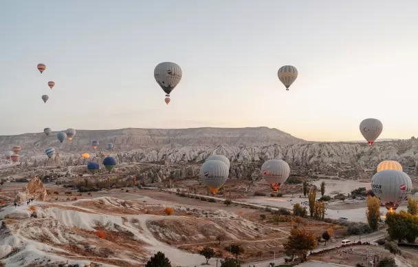 Many hot air balloons in the mountains at dawn